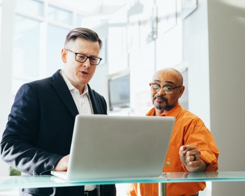 man using silver laptop beside another man